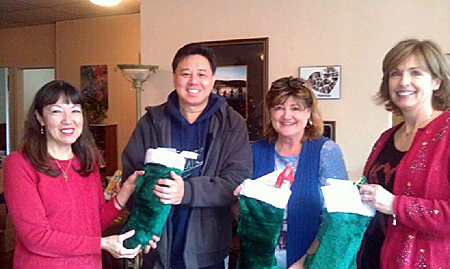 Chi Sing Li, Sheryl Serres, and Christine Story presenting stockings to Theresa Fusaro