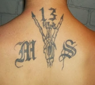 image of a tattoo on a man's back; a skeletal hand, the letters M and S and the number 13