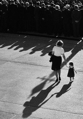 black and white photo of a woman walking while holding hands with a small child