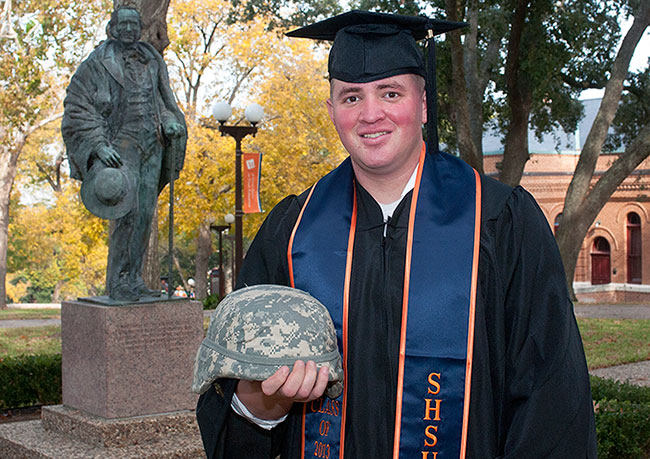 Leal wearing graduation garb and holding a helmet