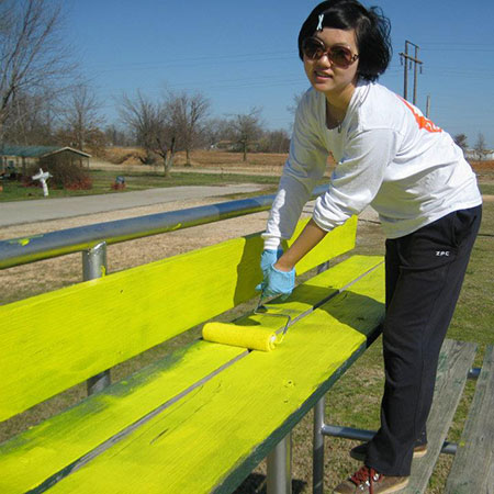 Yulu Ye painting a bench yellow