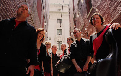 musicians wearing black and red smiling at the camera