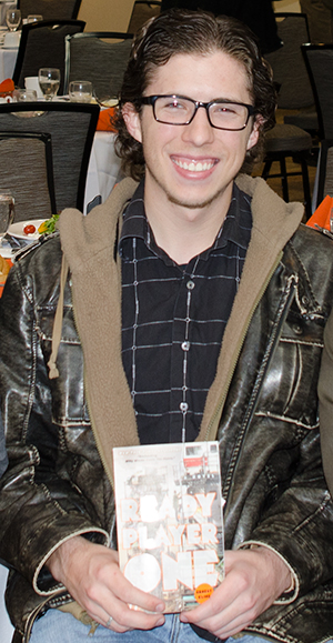 Caleb Crosby posing with a copy of Ready Player One