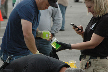 environmental workers holding jars of bright green water