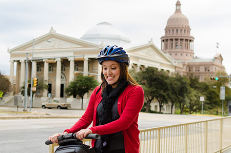 Melva Gomez smiling while riding a Segway down the street from the capitol building