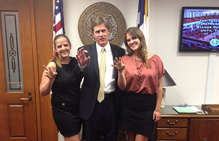 Miranda Landsman and her sister posing with Representative Dan Branch making the Bearkat claw for school spirit