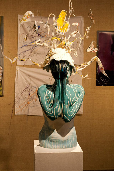 mixed media bust of a woman with her hands covering her face and wearing a hat with wires sticking out in different directions