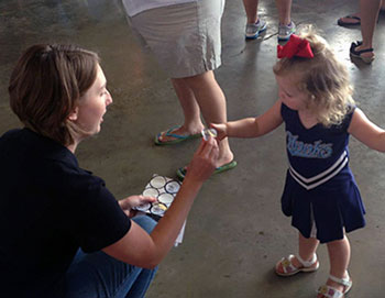 Shannon Posern handing a sticker to a little girl