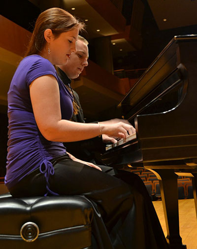 Ray and Jimenez sitting at the piano playing a duet