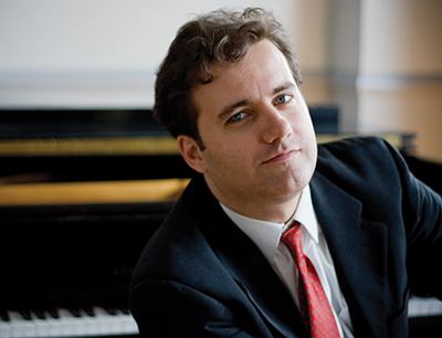 Josu De Solaun posing in front of a piano