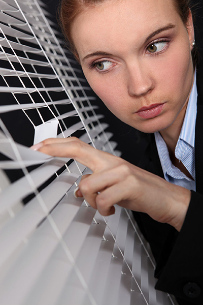 woman peeking through window blinds