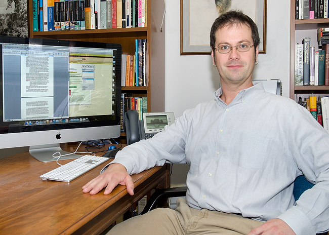 Demson poses for picture at his desk