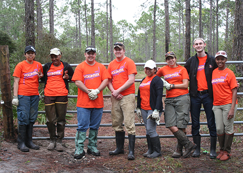 students wearing rain boots and posing in front of a fence