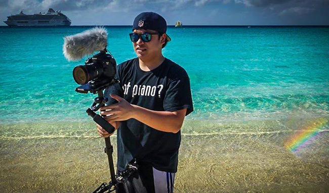 Khoi Nguyen holding film camera with Caribbean ocean and cruise ship in background