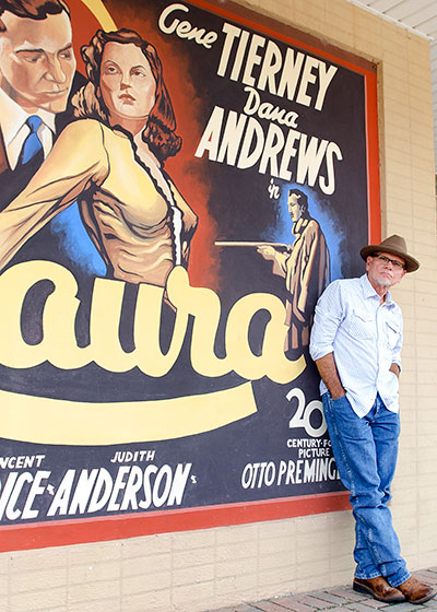 McCarley in front of old movie poster painting in front of theater