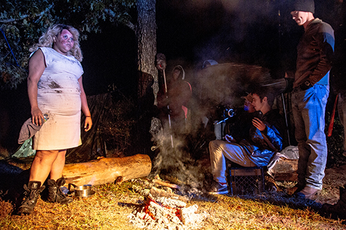 film still of people standing around a campfire