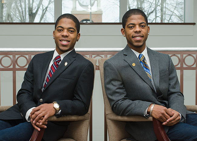 Varion and Darion Walton sitting in chairs, posing in mirror opposite