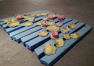 blue stained pieces of wood with pink flowers and yellow circular sitting on top