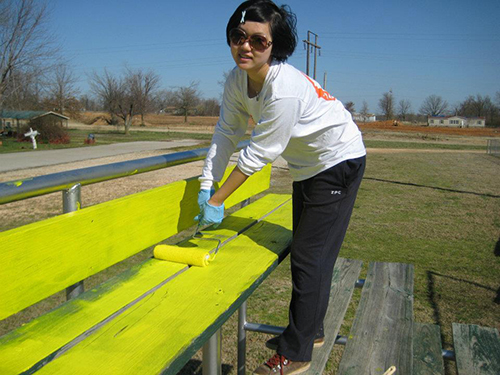 student painting a bench yellow